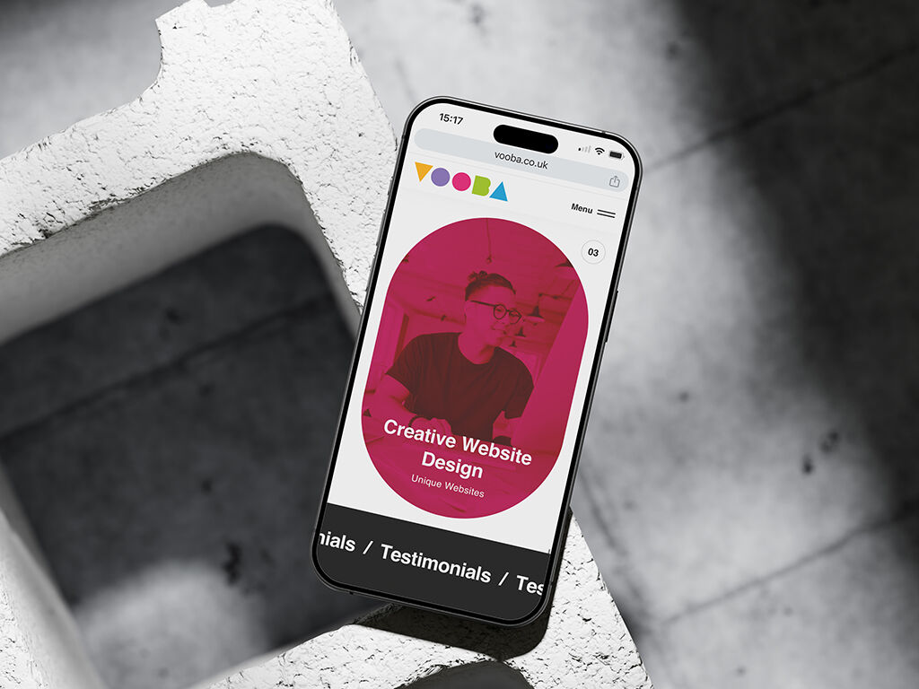 A smartphone displaying a website with a circular pink design on the screen, resting on a textured, concrete surface. The contrast between the dark and light areas highlights the Gestalt principle of figure-ground, where the viewer distinguishes the main subject (figure) from the background.